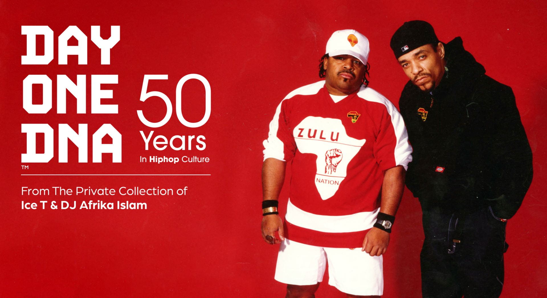 Afrika Islam and Ice T stand together looking seriously into the camera. Afrika is wearing a white baseball cap with an alien on it and a sweatshirt for Zulu Nation with a raised fist in the center of Africa. Ice T wears a black sweatshirt for Zulu Nation with a small Africa logo and a backwards black baseball hat.